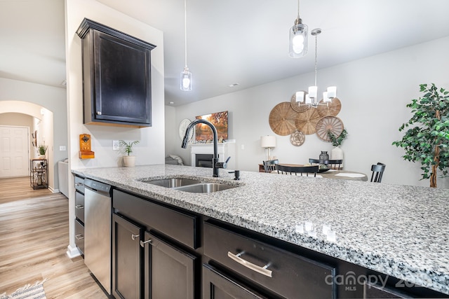 kitchen with light stone counters, dishwasher, sink, and pendant lighting