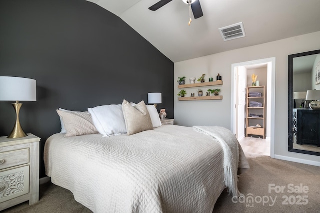 carpeted bedroom featuring vaulted ceiling, a walk in closet, and ceiling fan