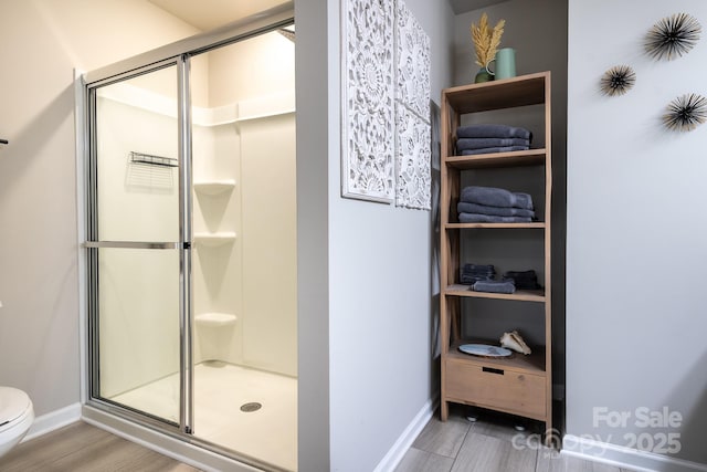 bathroom featuring a shower with door and toilet