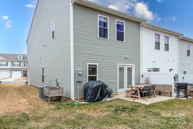 back of house featuring central AC unit, a patio area, and a lawn