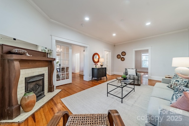 living room featuring light wood-type flooring, crown molding, and a fireplace