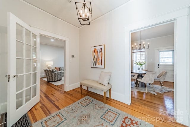 interior space with an inviting chandelier, ornamental molding, and hardwood / wood-style flooring