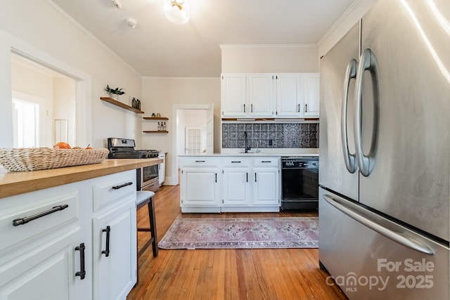 kitchen with white cabinets, appliances with stainless steel finishes, tasteful backsplash, light hardwood / wood-style floors, and crown molding