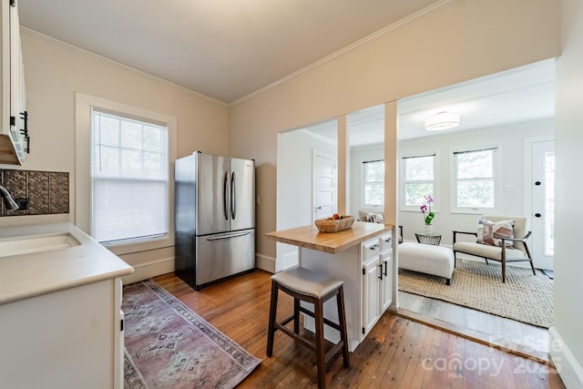 kitchen featuring a kitchen breakfast bar, sink, white cabinets, and stainless steel refrigerator