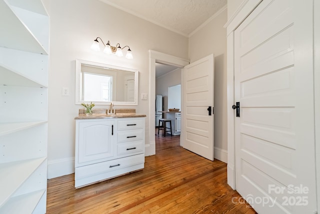 bathroom featuring ornamental molding, wood-type flooring, vanity, and a textured ceiling