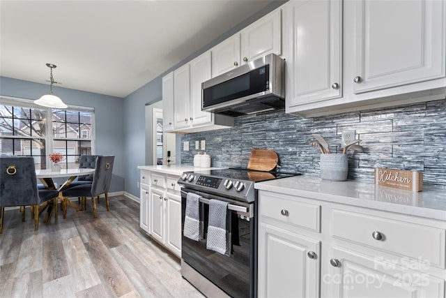 kitchen with pendant lighting, appliances with stainless steel finishes, light hardwood / wood-style floors, white cabinets, and decorative backsplash