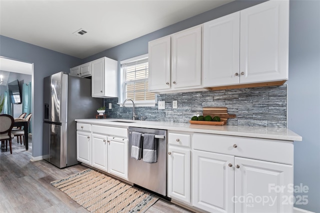 kitchen featuring light wood-type flooring, appliances with stainless steel finishes, sink, and white cabinets