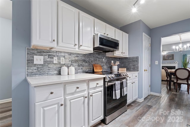 kitchen featuring stainless steel appliances, a notable chandelier, white cabinets, and decorative light fixtures