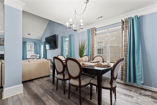 dining room with a notable chandelier, wood-type flooring, ornamental molding, and vaulted ceiling