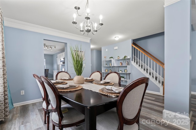 dining area with dark wood-type flooring, ornamental molding, and an inviting chandelier