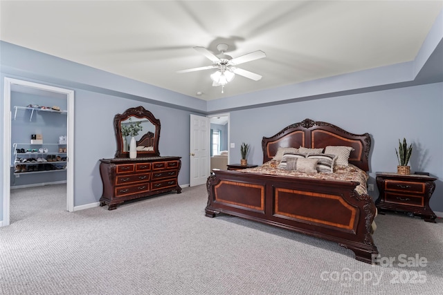 carpeted bedroom with ceiling fan and a spacious closet