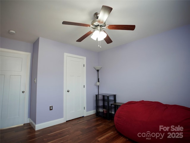 living area featuring ceiling fan and dark wood-type flooring