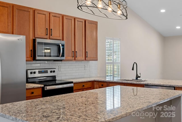 kitchen with appliances with stainless steel finishes, tasteful backsplash, sink, hanging light fixtures, and a center island