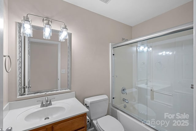 full bathroom featuring vanity, enclosed tub / shower combo, and toilet