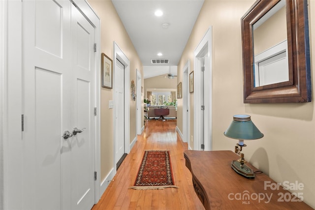 hall with light hardwood / wood-style floors and lofted ceiling