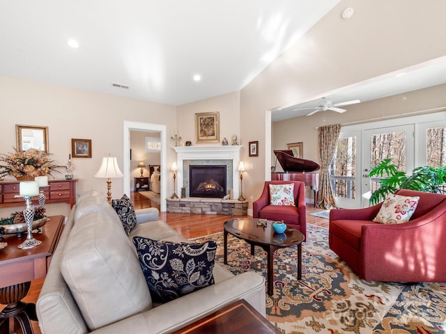 living room with ceiling fan, light hardwood / wood-style flooring, a fireplace, and lofted ceiling