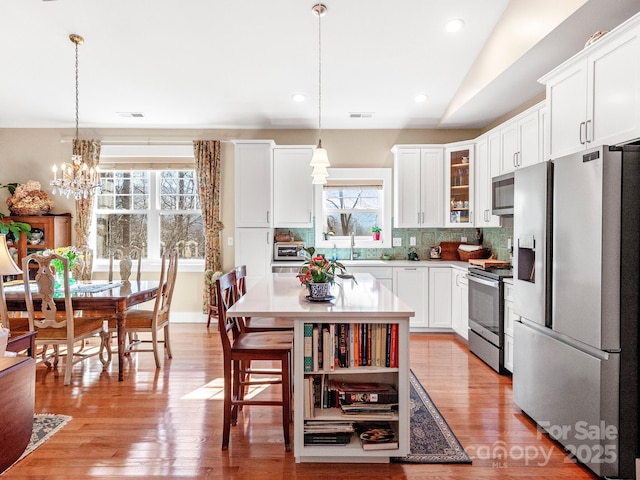 kitchen with a kitchen island, tasteful backsplash, pendant lighting, and appliances with stainless steel finishes