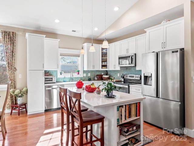 kitchen with white cabinets, vaulted ceiling, a center island, and appliances with stainless steel finishes