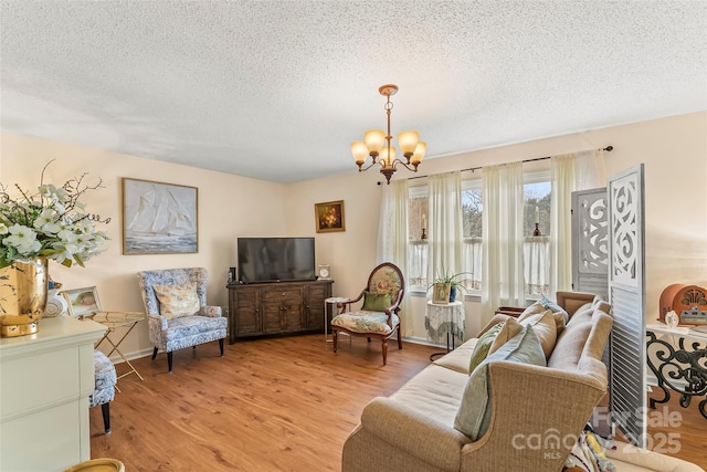 living room with a textured ceiling, a notable chandelier, and light hardwood / wood-style floors