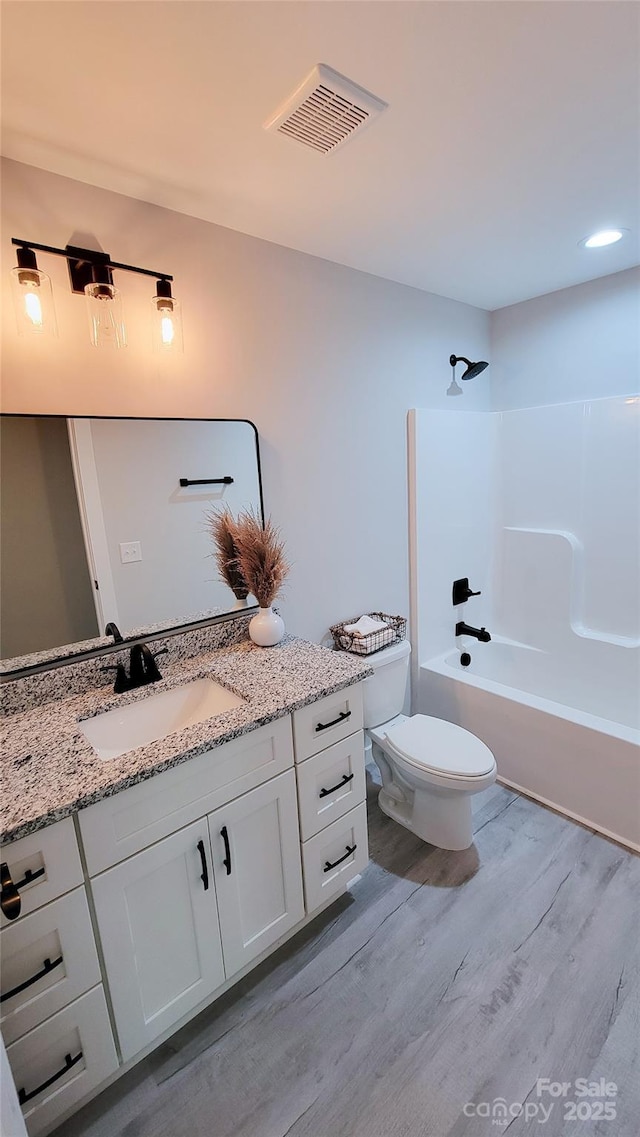 full bath featuring shower / tub combination, toilet, wood finished floors, vanity, and visible vents