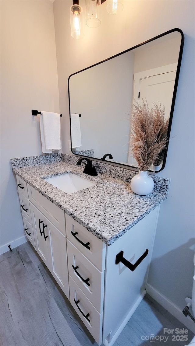 bathroom with wood finished floors, vanity, and baseboards