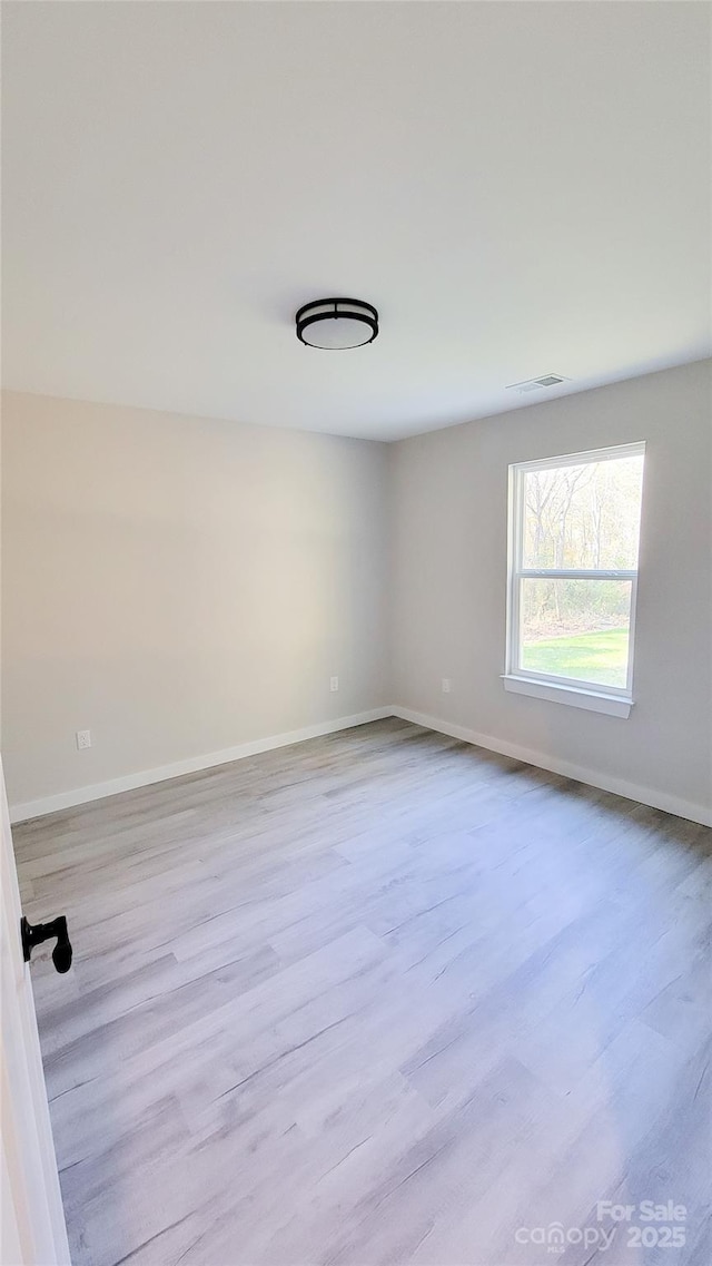 spare room featuring visible vents, baseboards, and wood finished floors