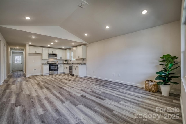 unfurnished living room with high vaulted ceiling, recessed lighting, a sink, baseboards, and light wood-style floors