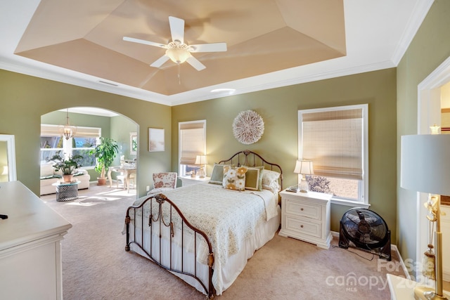 carpeted bedroom featuring ceiling fan with notable chandelier, ornamental molding, and a raised ceiling