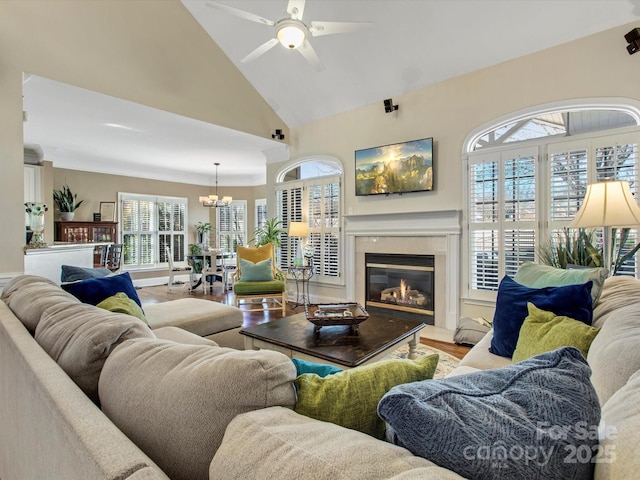 living room with ceiling fan with notable chandelier, hardwood / wood-style floors, and high vaulted ceiling