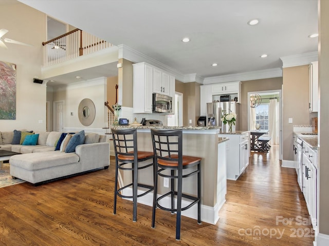 kitchen with white cabinets, light stone countertops, a breakfast bar, a kitchen island, and stainless steel appliances