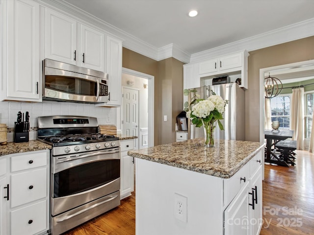 kitchen featuring light stone countertops, white cabinets, a center island, and stainless steel appliances