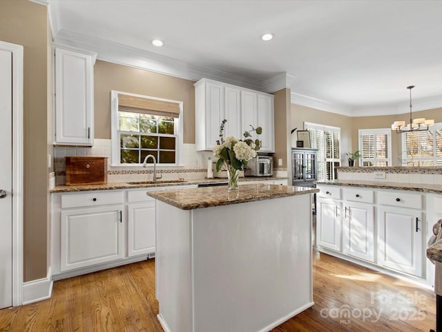 kitchen featuring sink, a kitchen island, and white cabinetry