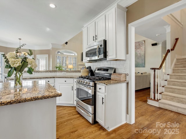 kitchen featuring stone counters, appliances with stainless steel finishes, decorative backsplash, white cabinets, and light wood-type flooring