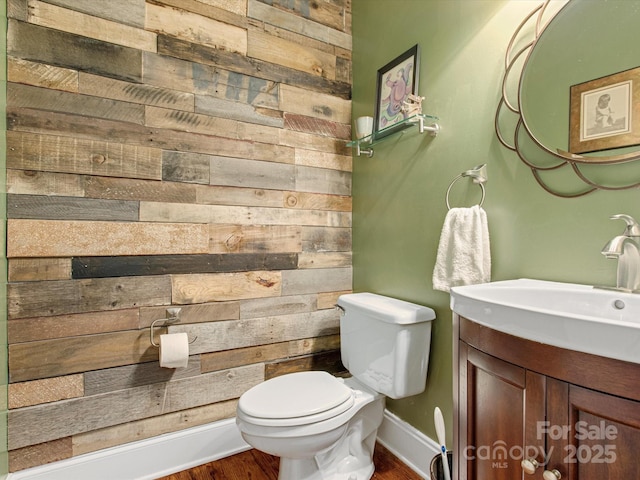 bathroom with vanity, toilet, wood walls, and hardwood / wood-style floors