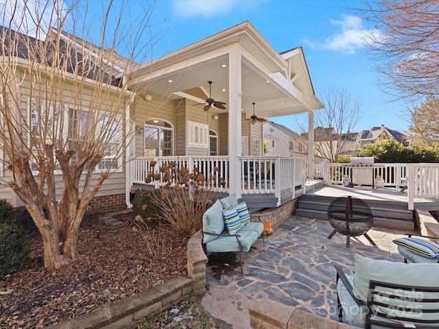 exterior space with ceiling fan, a patio area, a wooden deck, and a fire pit