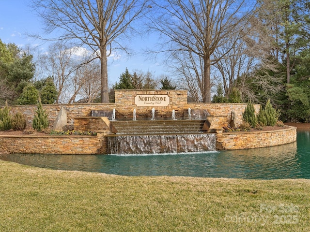 community / neighborhood sign with a yard and a water view