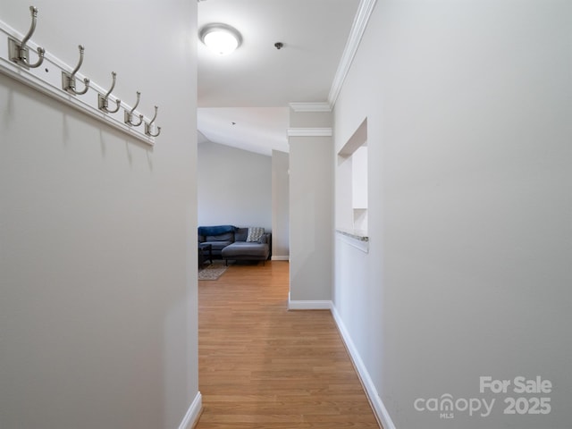 hallway with crown molding, baseboards, and light wood-type flooring