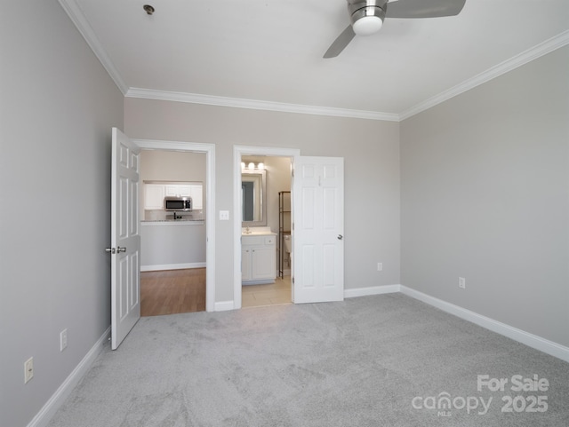 unfurnished bedroom with a ceiling fan, baseboards, ensuite bath, ornamental molding, and light carpet