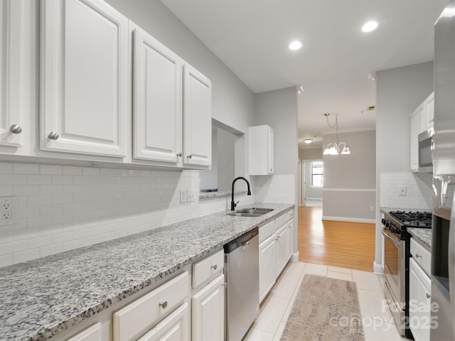 kitchen featuring stainless steel appliances, white cabinetry, light tile patterned floors, and a chandelier