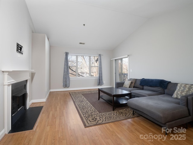 living room with baseboards, visible vents, high vaulted ceiling, a fireplace, and light wood-type flooring