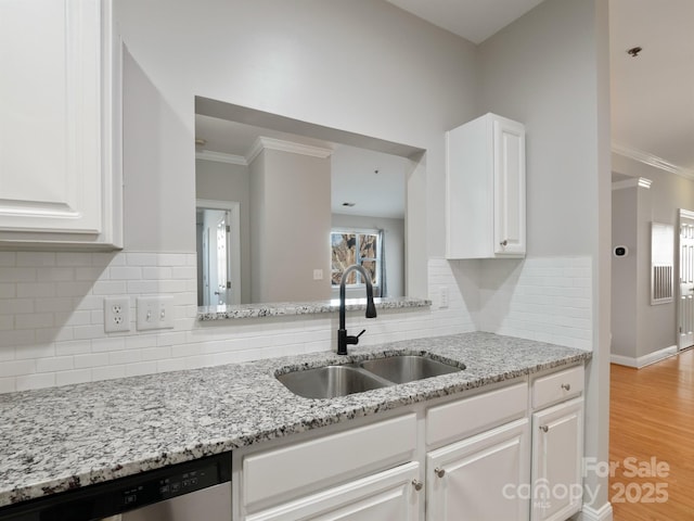 kitchen featuring a sink, stainless steel dishwasher, white cabinetry, crown molding, and light stone countertops