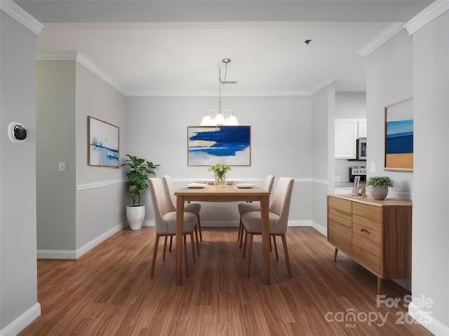 dining area featuring light wood-type flooring, crown molding, an inviting chandelier, and baseboards