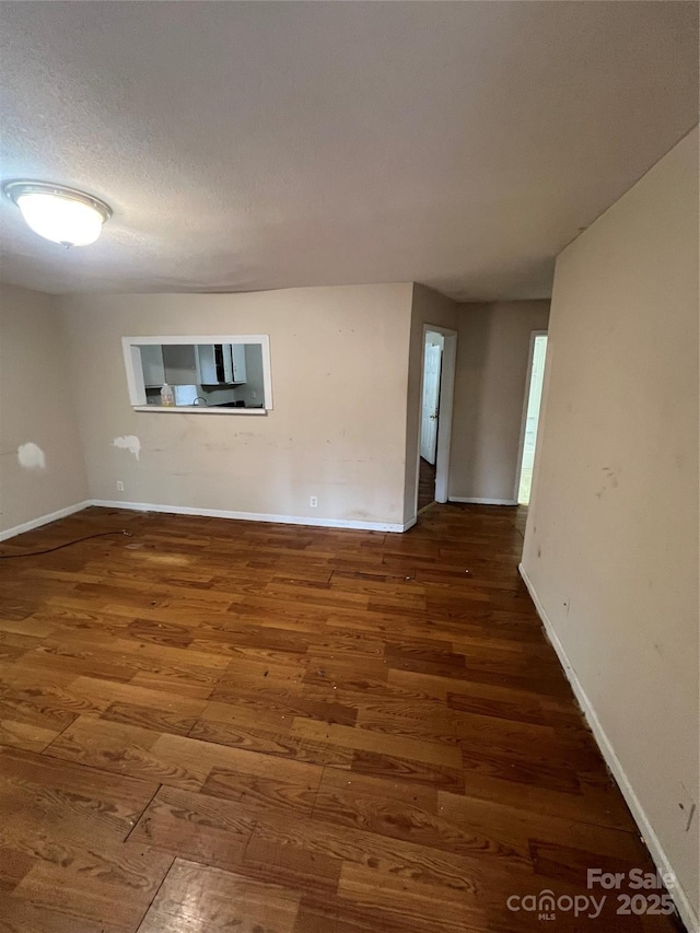 empty room with dark hardwood / wood-style floors and a textured ceiling