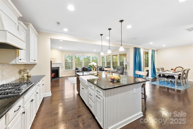 kitchen featuring dark wood-style flooring, stainless steel gas cooktop, decorative backsplash, a fireplace with flush hearth, and open floor plan