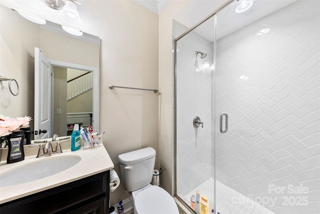 bathroom with toilet, vanity, crown molding, and a shower stall
