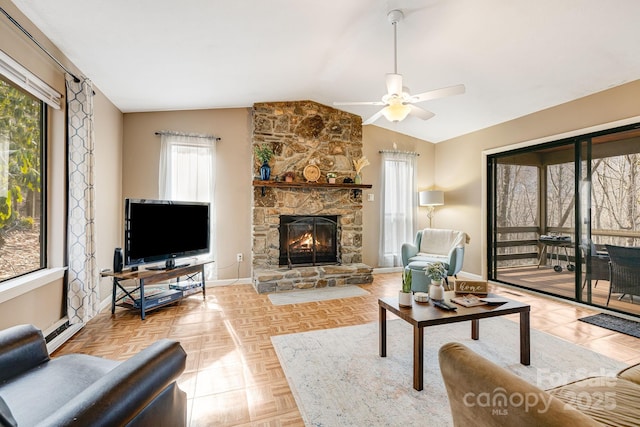 living room with ceiling fan, light parquet flooring, a stone fireplace, and vaulted ceiling