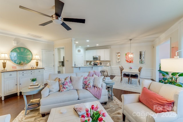 living room featuring ceiling fan, ornamental molding, and light hardwood / wood-style floors