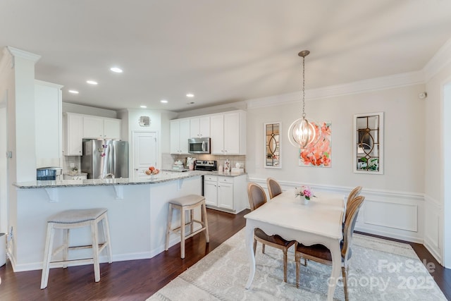 kitchen with white cabinetry, appliances with stainless steel finishes, decorative backsplash, and decorative light fixtures