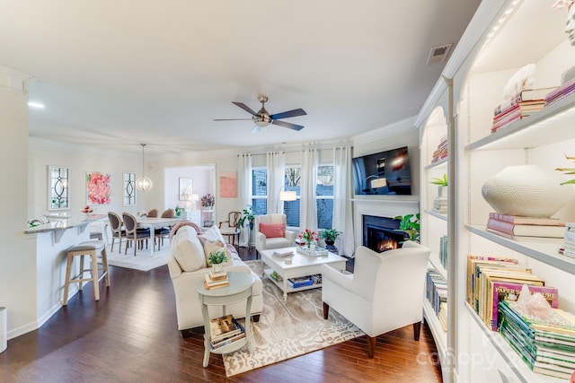 living room featuring dark wood-type flooring, ceiling fan, and ornamental molding