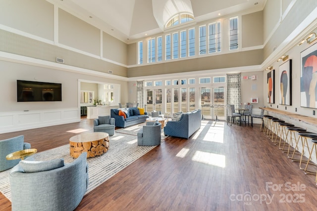 living room with wood-type flooring and a towering ceiling